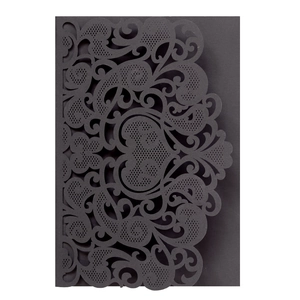 Macro view of black laser-cut invitation cover with intricate scroll and floral patterns