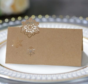 Close-up of laser-cut snowflake kraft paper table card on a white dinner plate