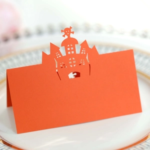 Detail of laser-cut Halloween castle and skull table card in bright orange on a plate