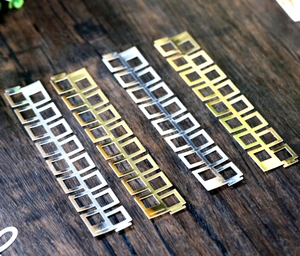 Detailed view of hollow square mesh napkin rings in reflective gold and silver finishes