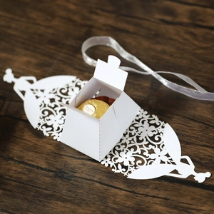 Detailed laser-cut white wedding favor box with floral patterns and a chocolate inside