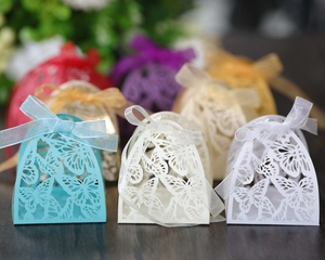 Detail of laser-cut butterfly wedding candy boxes in various colors with organza ribbons