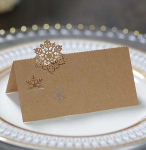 Detailed view of brown kraft paper place card with delicate snowflake cutouts on a plate