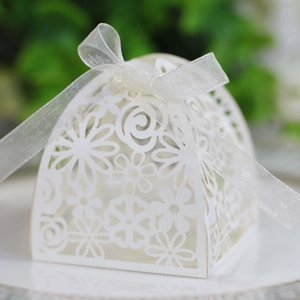 Close-up of elegant white laser-cut wedding candy box with floral patterns and ribbon