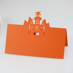 Detailed laser-cut castle and skull patterns on a vibrant orange Halloween place card