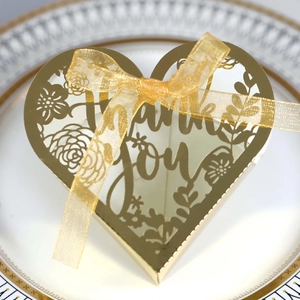 Close-up of golden heart-shaped laser-cut gift box with Thank You text and ribbon