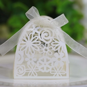 Macro shot of white laser-cut floral wedding candy box with elegant organza ribbon