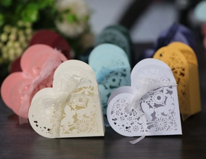 Macro detail of laser-cut heart favor boxes with butterflies and organza ribbons
