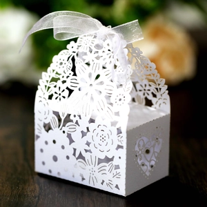 Close-up of laser-cut wedding candy box with floral patterns and white organza ribbon
