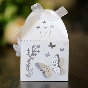 Close-up of white laser-cut wedding favor box with butterfly patterns and ribbon bow
