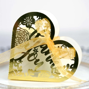 Macro view of gold heart-shaped laser cut wedding favor box with Love text and ribbon