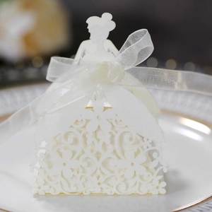 Detail of laser-cut bridal dress paper candy box with white ribbon on a gold-rimmed tray