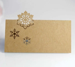 Macro shot of laser-cut snowflake details on brown kraft paper holiday place card
