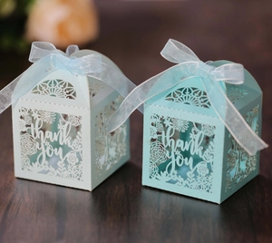 Detail of laser-cut thank you gift box with floral pattern and blue organza ribbon