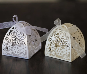 Detail of laser-cut heart and floral patterns on white pearlescent wedding favor boxes
