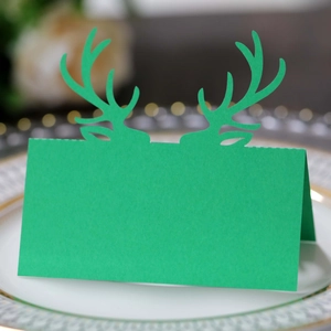 Macro di segnaposto natalizio verde con corna ritagliate su piatti eleganti e festivi