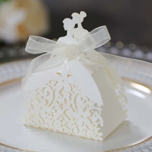 Intricate laser-cut wedding favor box with bride and groom silhouette and white ribbon