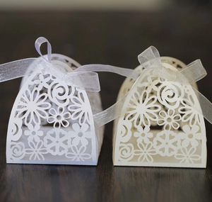 Detailed laser-cut floral pattern on wedding candy boxes with white ribbon closure