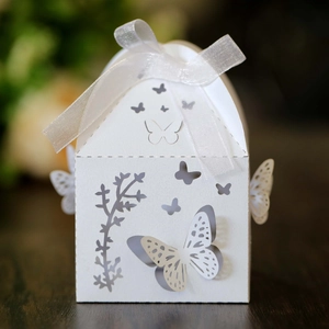 Detail of white butterfly laser-cut gift box with sheer organza ribbon on wood surface