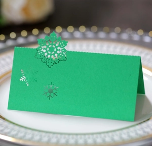 Detail of green laser-cut snowflake place card on white plate for Christmas party