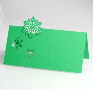 Detail of laser-cut grass green snowflake place card with elegant hollowed-out patterns