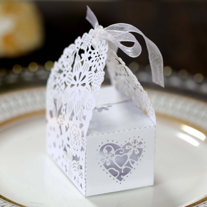Macro shot of white laser-cut wedding favor box with floral patterns and organza ribbon