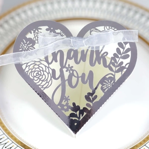Macro shot of silver mirror heart favor box with laser-cut thank you text and bow
