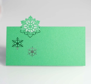 Detail of green wedding place card with intricate laser cut snowflake paper craftsmanship