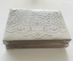 Detailed macro view of laser-cut floral pattern on grey wedding invitation envelopes