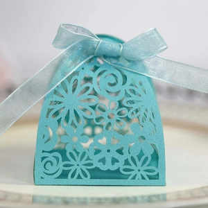 Detail of laser-cut teal wedding favor box with daisy pattern and organza ribbon bow