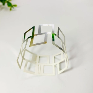 Macro shot of silver geometric cutout napkin ring with square pattern on white background