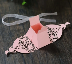 Detail of pink laser-cut candy box featuring floral patterns and a ribbon tie