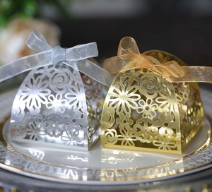Detail of laser-cut floral candy boxes with organza ribbons in gold and silver