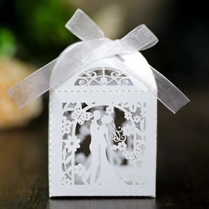 Detailed laser-cut white wedding favor box with bride and groom silhouette and ribbon
