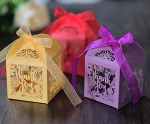 Detail of laser-cut thank you gift boxes with intricate floral patterns and silk ribbons