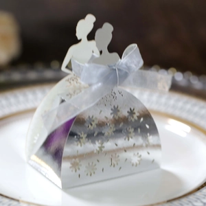 Detail of silver laser-cut wedding candy box with bride silhouettes and blue ribbon