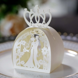 Detail of white laser-cut wedding favor box with crown top and couple silhouette