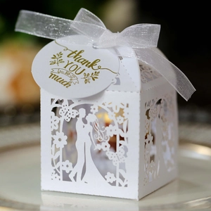 Laser cut white wedding favor box with ribbon and gold foil thank you tag on a tray