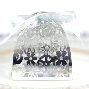 Macro shot of silver laser-cut hollow candy box with intricate floral patterns and blue ribbon