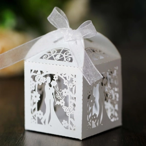 Macro detail of laser-cut wedding favor box with bride and groom pattern and white ribbon