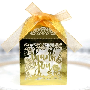Detail of laser-cut hollow golden gift box with thank you text and ribbon bow