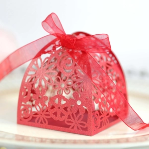 Close-up of red laser-cut hollow floral gift box with silk ribbon bow on elegant plate