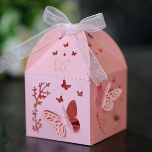 Macro shot of laser-cut butterfly candy box with pink hollow patterns and ribbon bow