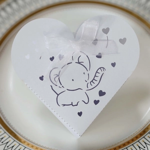 Dettaglio di una scatola di caramelle a cuore bianca con elefante e nastro in raso