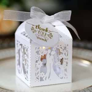 Macro shot of white laser-cut wedding favor box with ribbon and Thank You tag