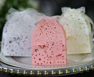Macro detail of laser-cut floral patterns on colorful favor boxes with organza ribbons