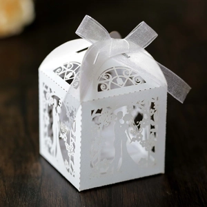 Macro shot of laser-cut white wedding favor box with bride and groom silhouette