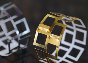 Close-up of geometric hollow napkin rings in gold and silver finish with metallic shine