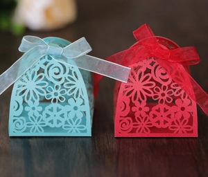 Detail of laser-cut floral candy boxes in blue and red with delicate organza ribbons