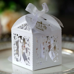 Detail of white laser-cut wedding favor box with butterfly pattern and heart thank you tag